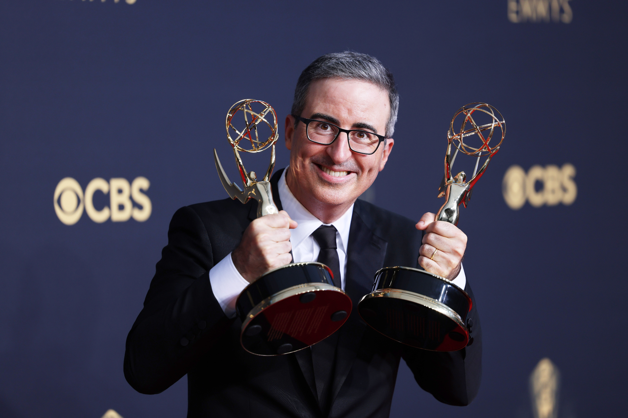 'Last Week with John Oliver' host John Oliver, who talked about 'Air Bud' holding two Emmy Awards and smiling in front of step and repeat