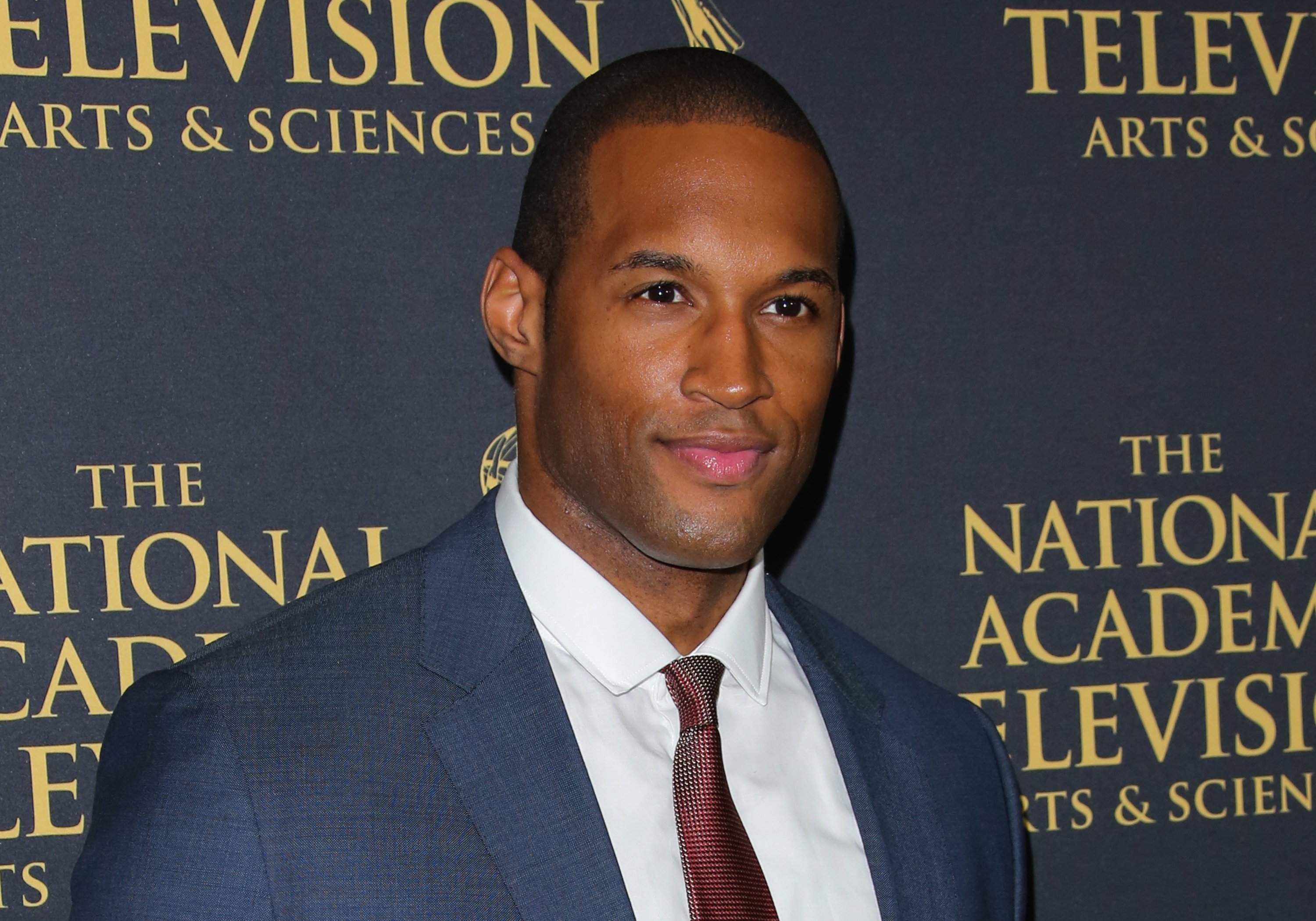 'The Bold and the Beautiful' actor Lawrence Saint-Victor wearing a blue suit, white shirt, and burgundy tie.