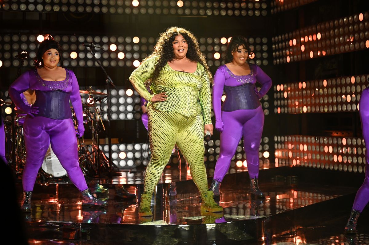 Lizzo wearing a green sequin jumpsuit while performing on SNL.