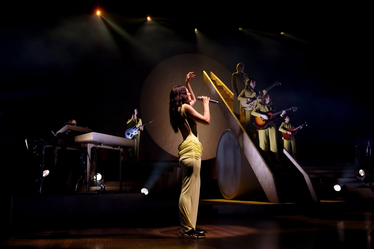 Wearing a floor length dress, Lorde sings on stage during a tour performance in Nashville, TN.