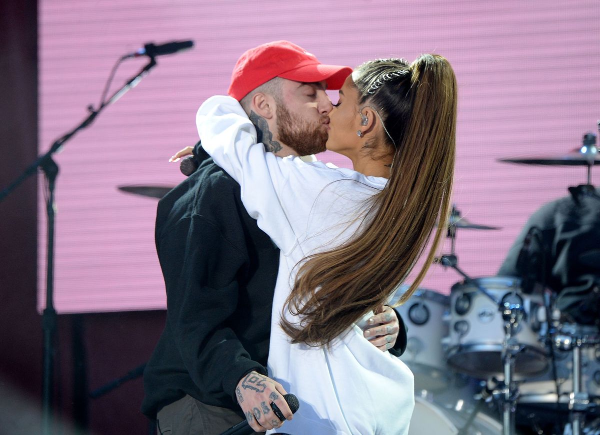 Mac Miller and Ariana Grande kiss on stage during a performance.