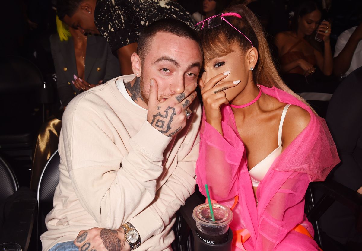 Mac Miller and Ariana Grande pose with their hands covering their mouths.