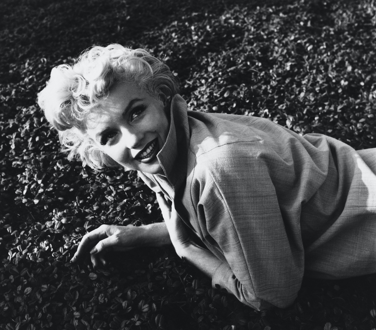 Marilyn Monroe smiling, lying on the grass, in black and white