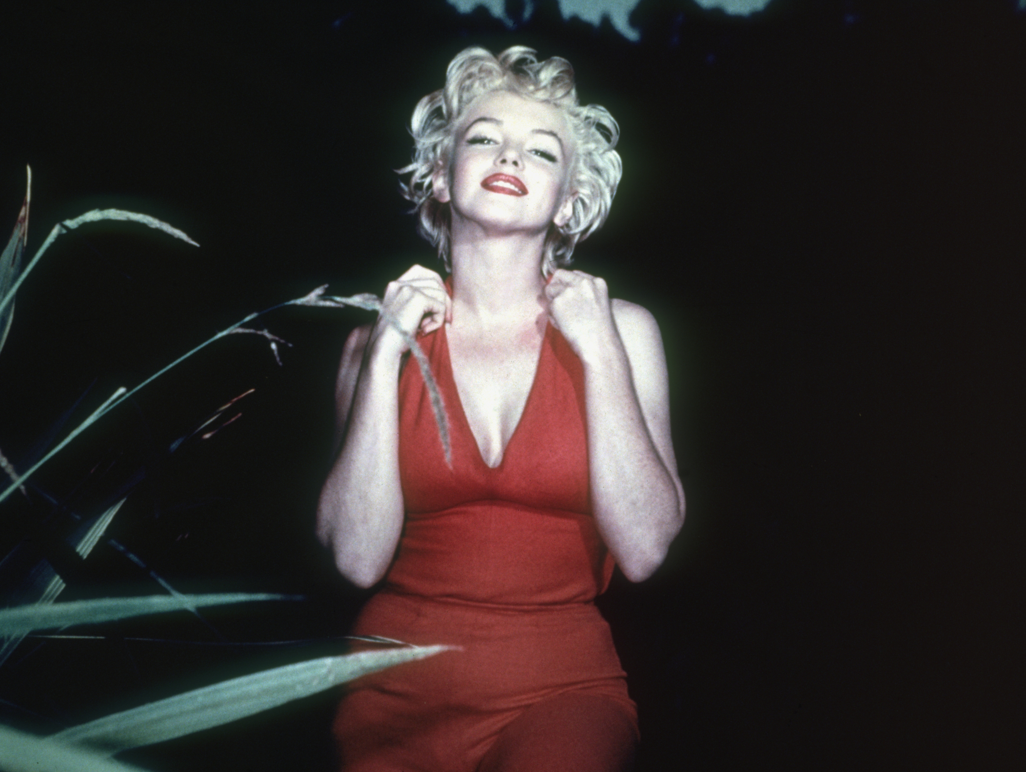 Marilyn Monroe, the subject of the biopic 'Blonde' in a red dress smiling with her chin held high