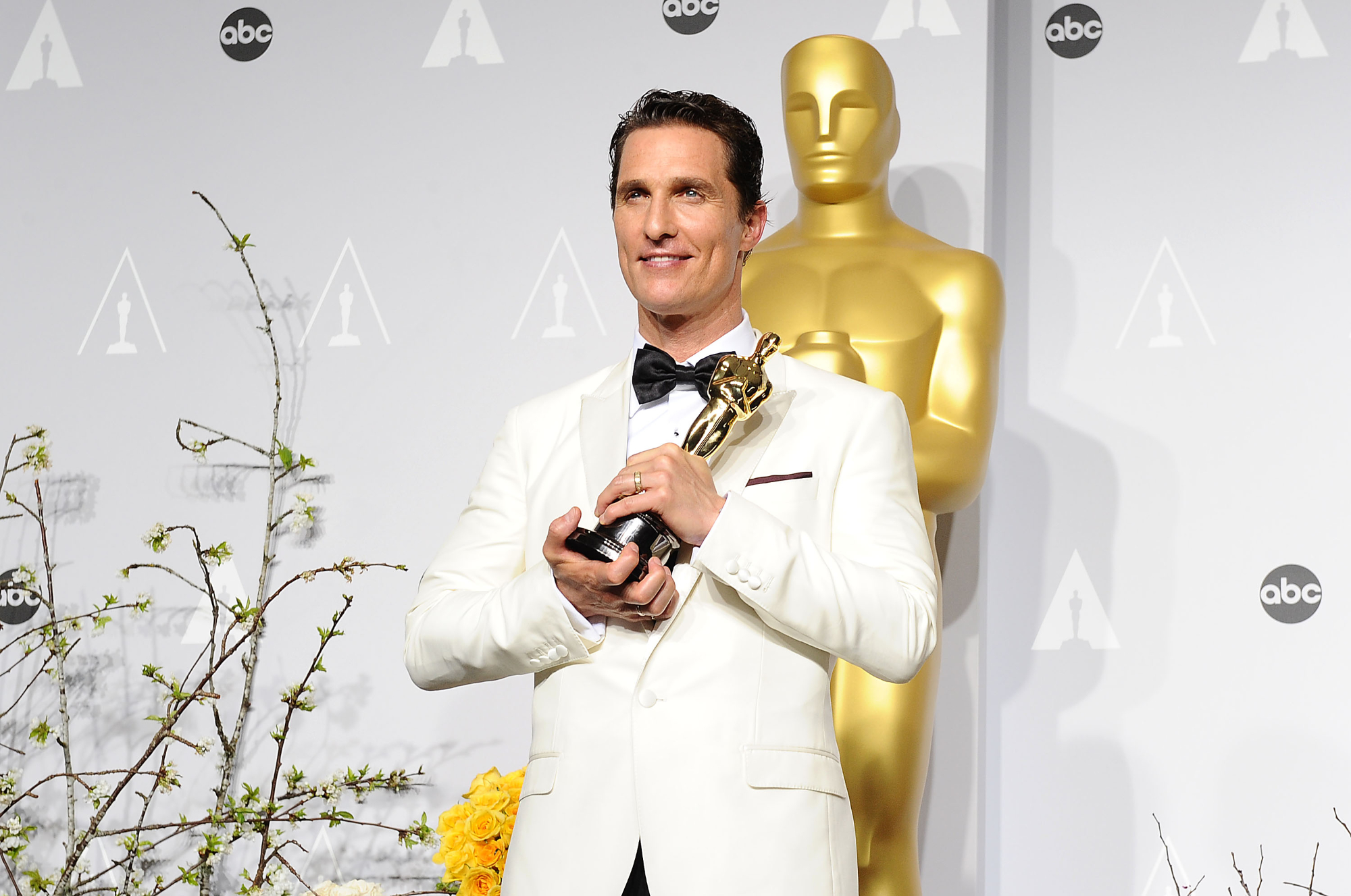 Matthew McConaughey, father of three kids holding an Oscar wearing a white suit