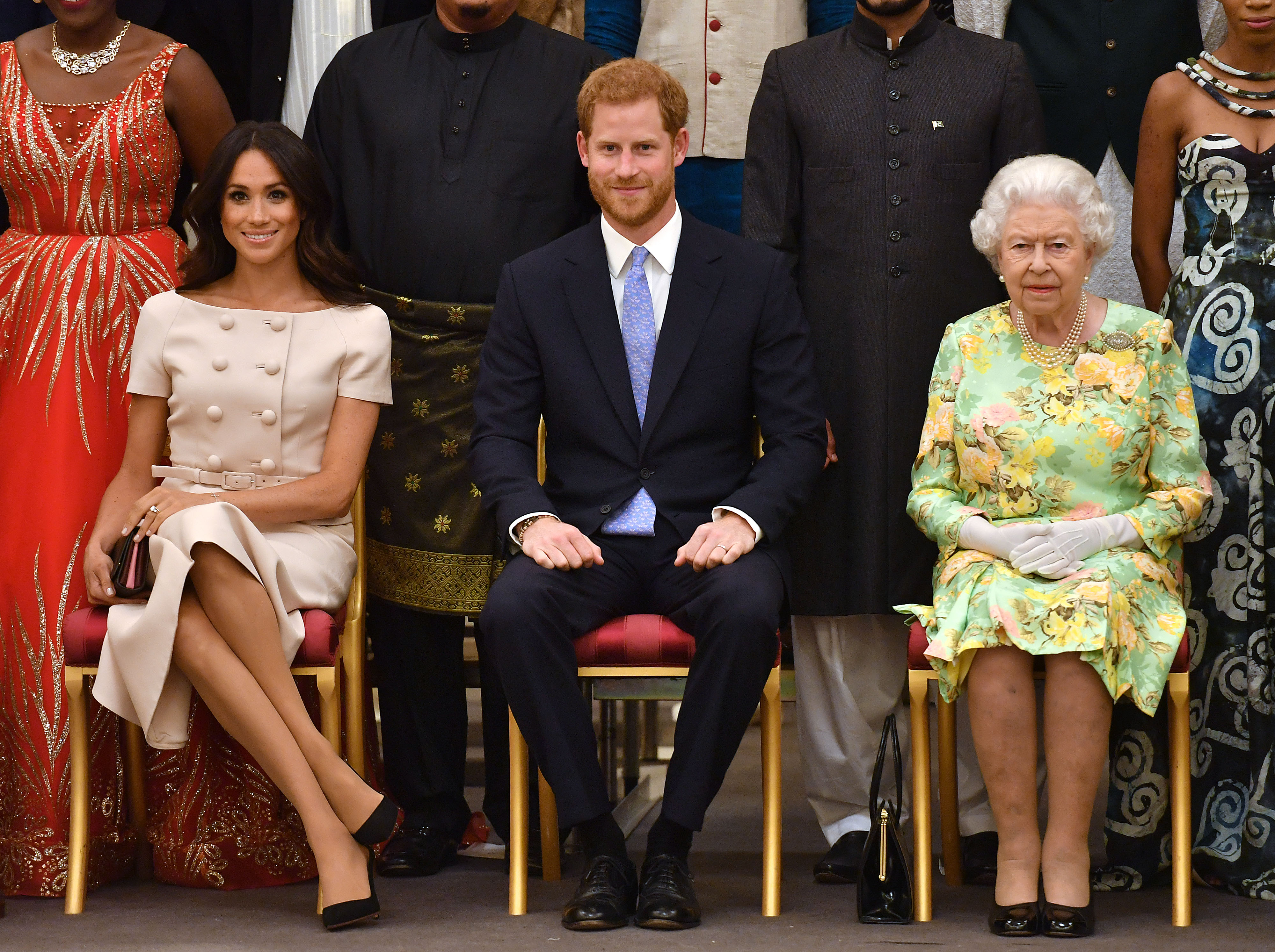 Meghan Markle, Prince Harry, and Queen Elizabeth II sitting next to each other at the Queen's Young Leaders Awards Ceremony at Buckingham Palace