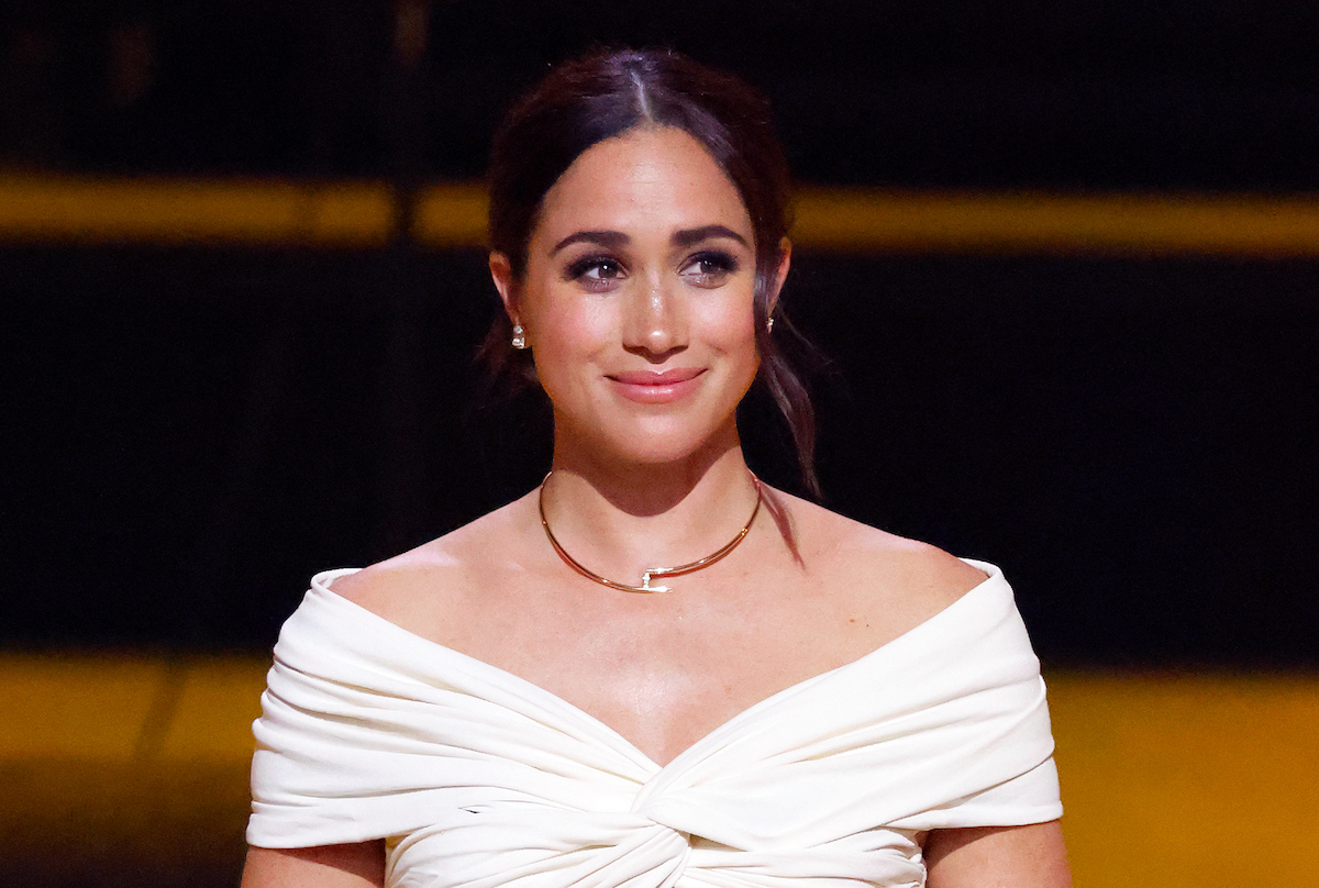 Royal family member Meghan Markle smiles wearing a white off the shoulder top at the Invictus Games