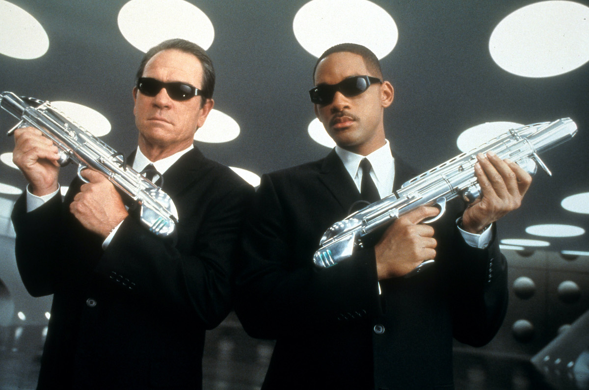 ‘Men in Black’ stars Tommy Lee Jones and Will Smith wear black suits and sunglasses as they hold their weapons up