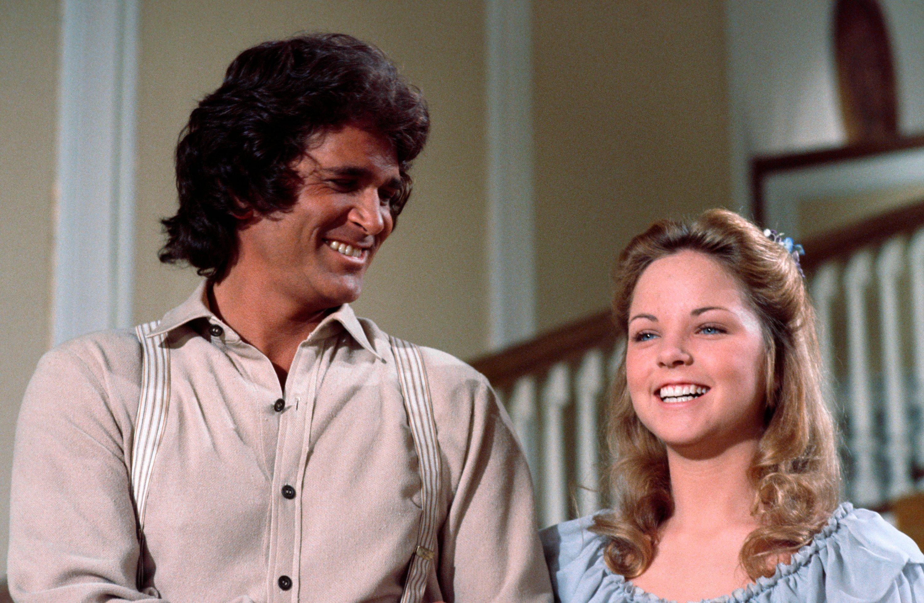 Michael Landon smiles while standing next to Melissa Sue Anderson on the set of Little House on the Prairie.