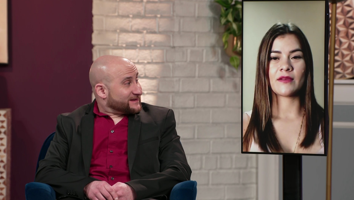 Mike wearing a red shirt and a suit jacket during the '90 Day Fiancé: Before the 90 Days' Season 5 tell-all, sitting next to Ximena who is on a screen.