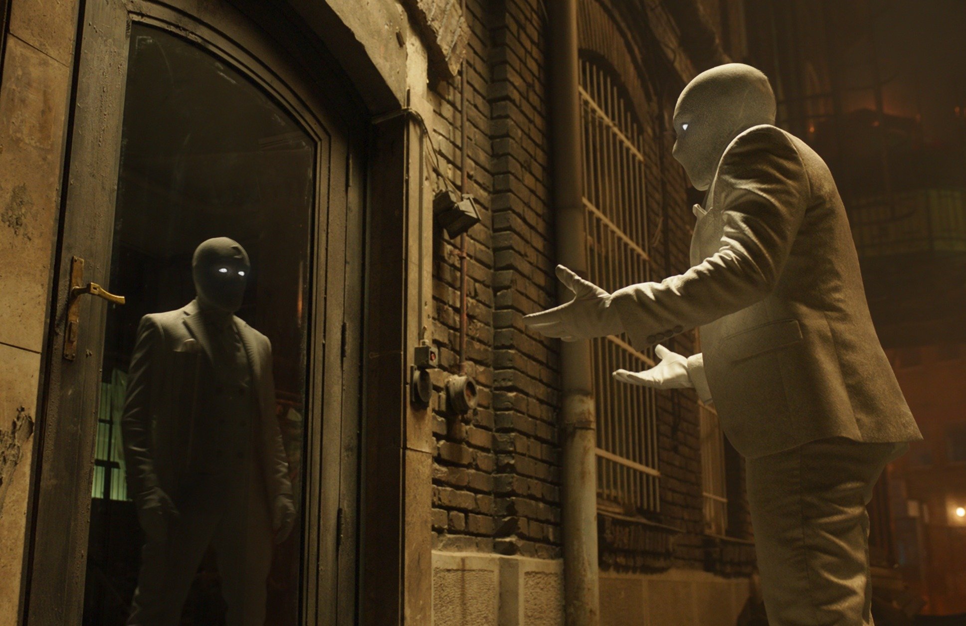 Oscar Isaac as Steven Grant and Marc Spector in Marvel's 'Moon Knight' Episode 2. He's wearing the suit, and Steven is speaking to Marc in his reflection.