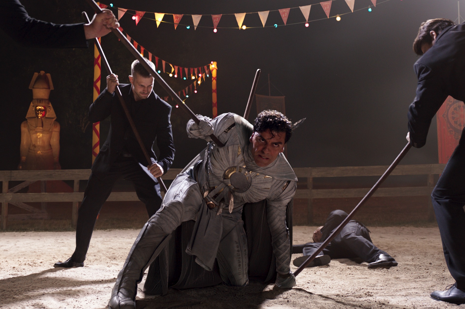 Oscar Isaac in 'Moon Knight' Episode 3. He's fighting three men and kneeling as he defends himself.