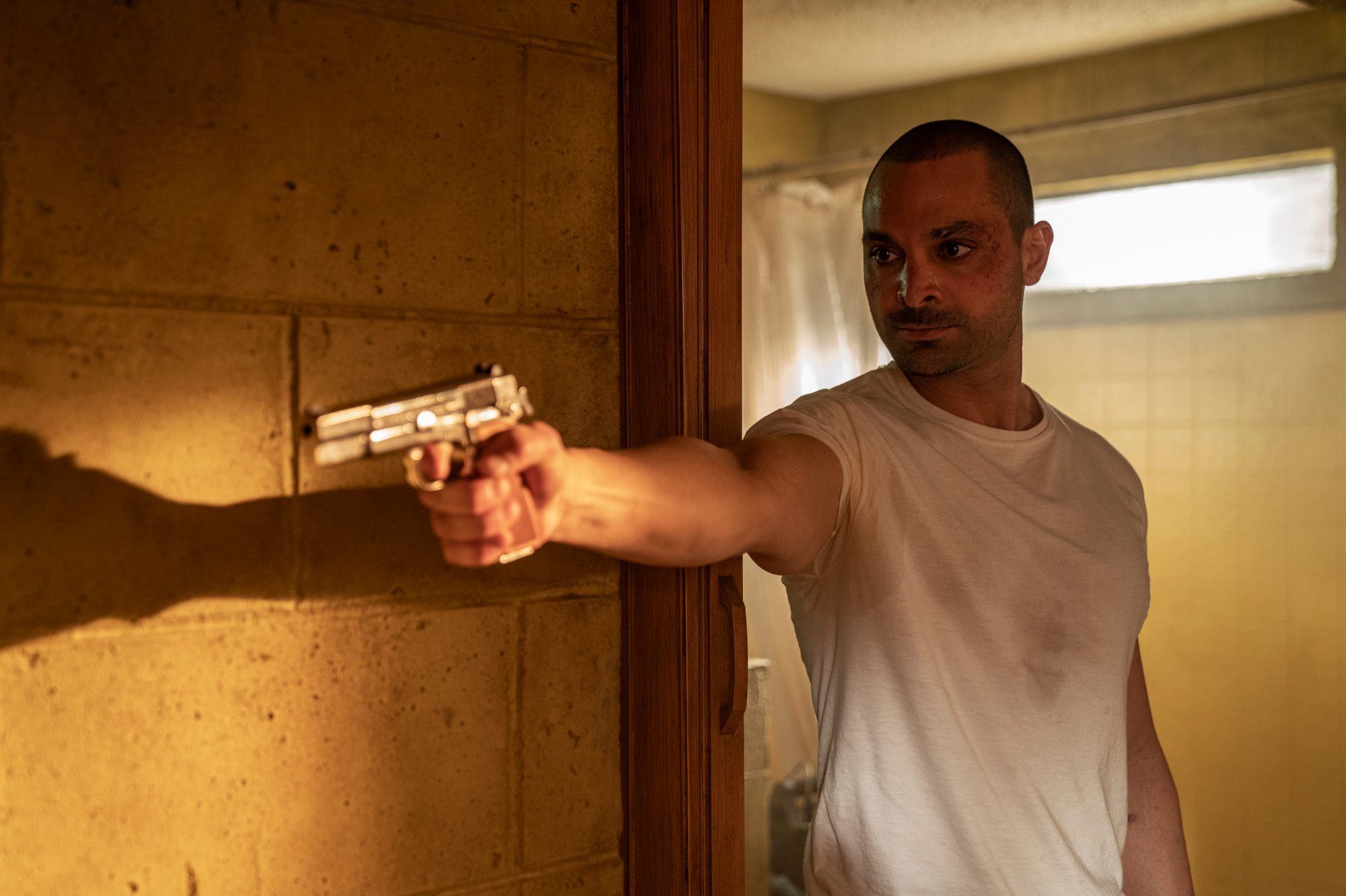 Michael Mando as Nacho Varga in 'Better Call Saul' Season 6 Episode 2. He's standing in a motel and pointing a gun at someone off screen.