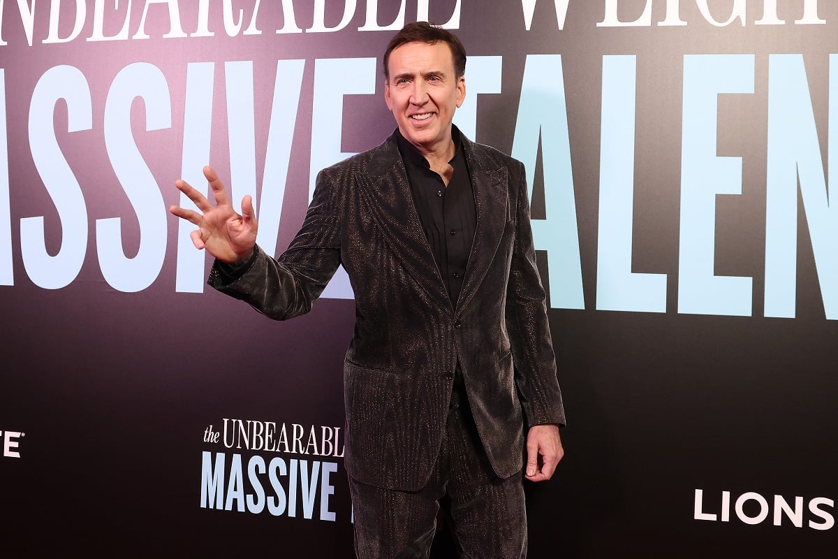 Nicolas Cage smiling while wearing a black suit.