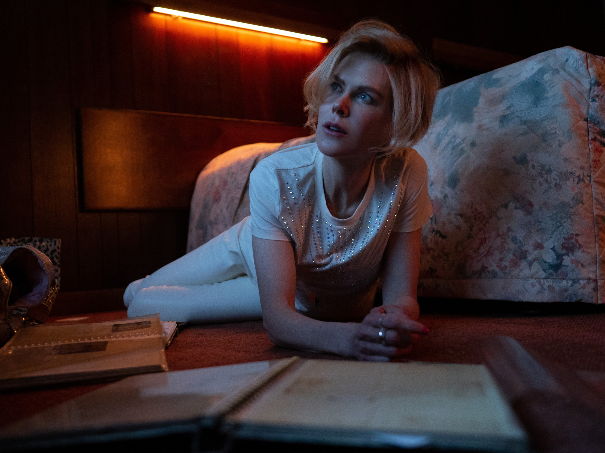 Nicole Kidman in 'Roar' Episode 2 on Apple TV+. She's lying on the floor with a photo album in front of her.