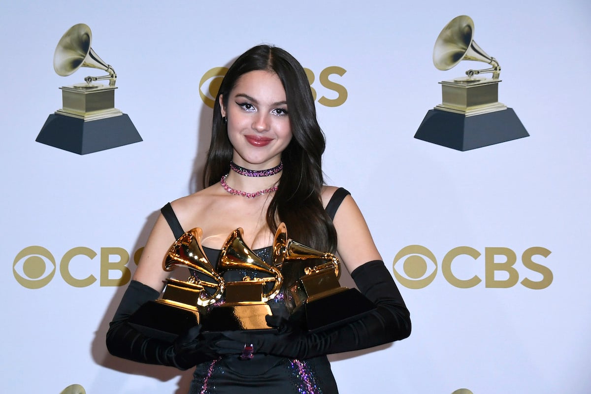Olivia Rodrigo holds three trophies at the 2022 Grammy Awards.