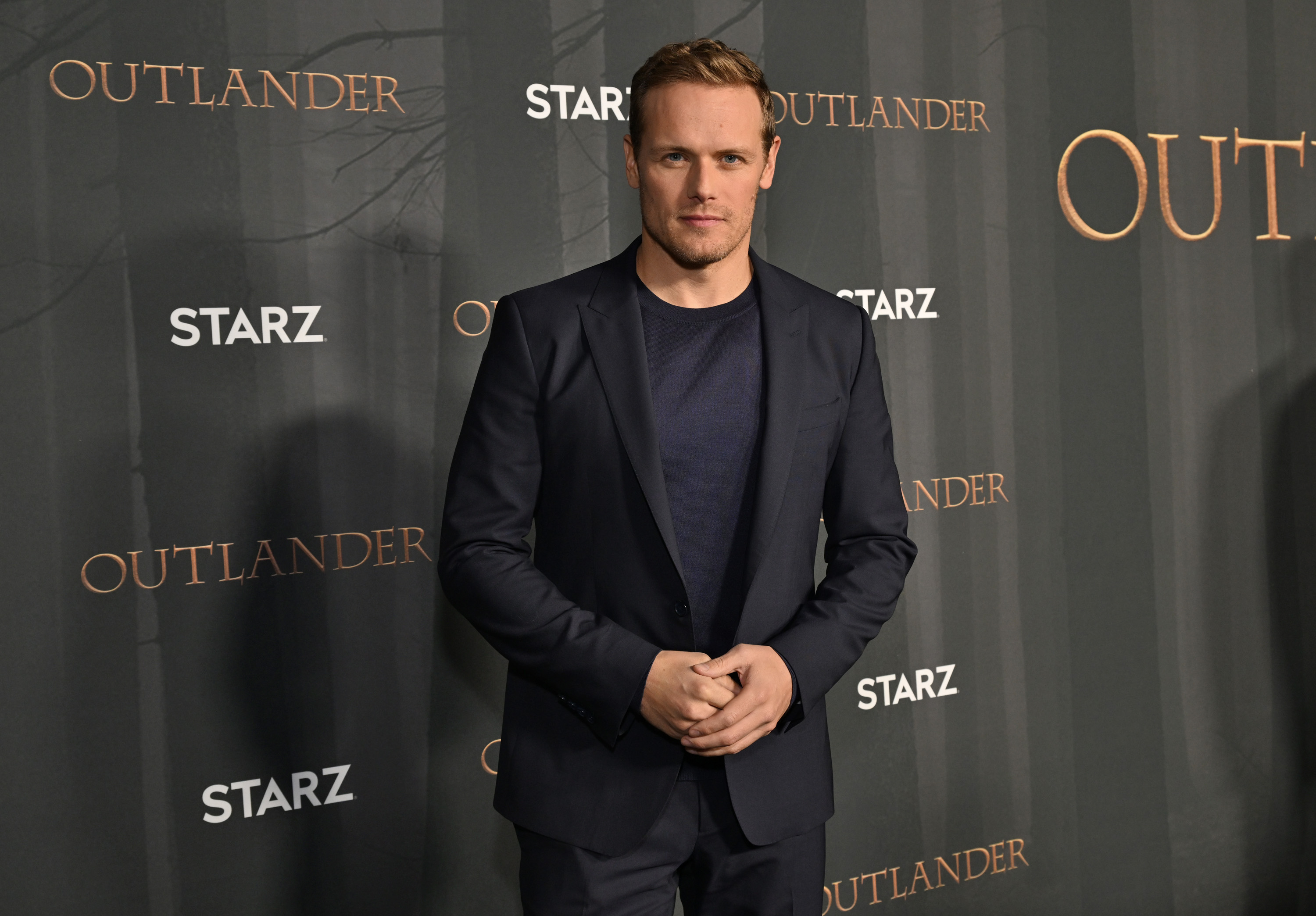 'Outlander': Sam Heughan clasps his hands on the red carpet