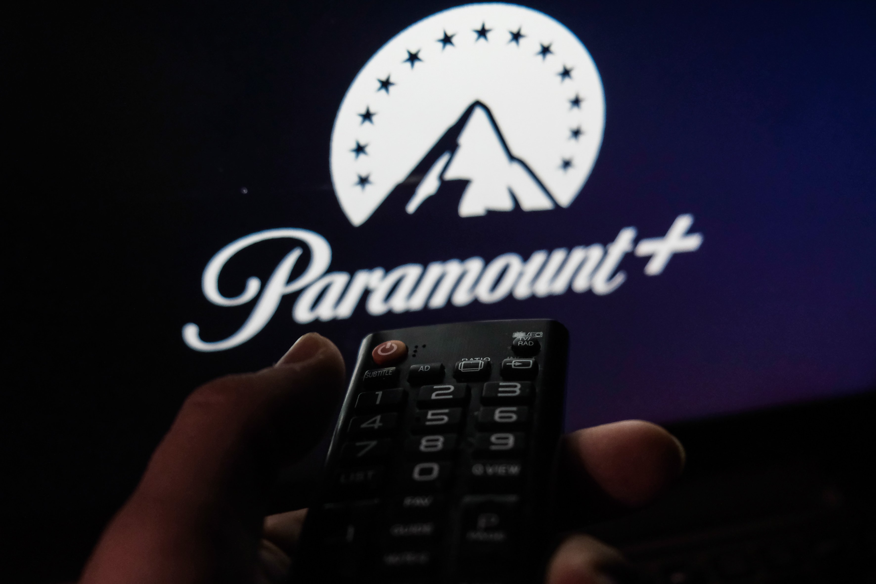 TV remote control is seen with Paramount+ logo displayed on a screen