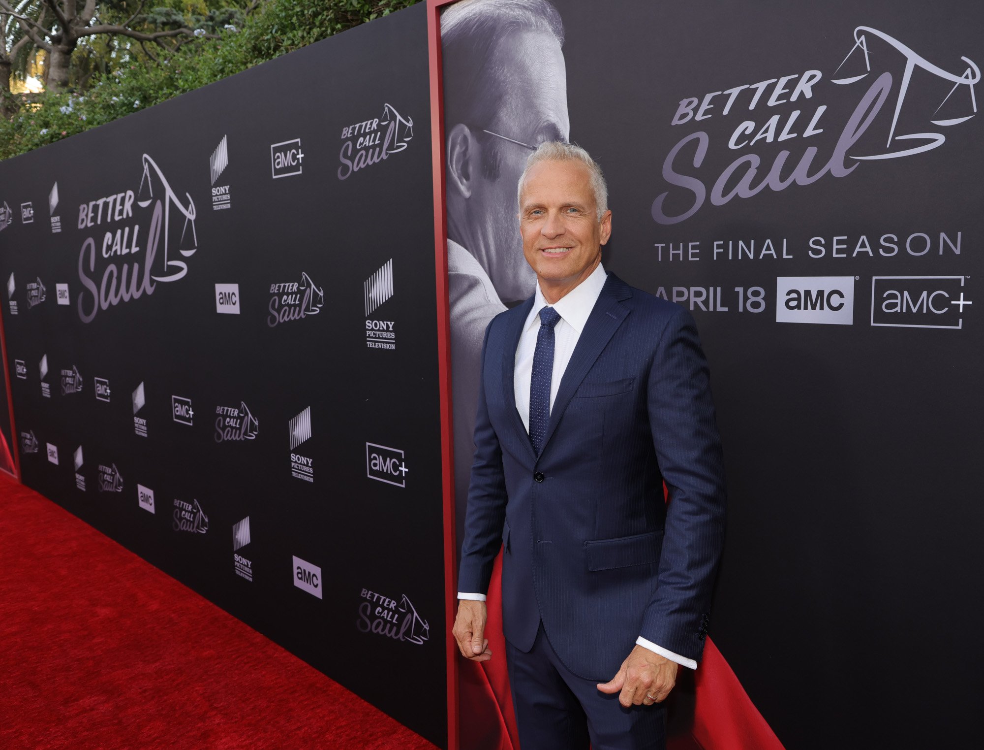 Patrick Fabian at the premiere for 'Better Call Saul' Season 6. He's wearing a suit and standing in front of a wall with Bob Odenkirk on it.