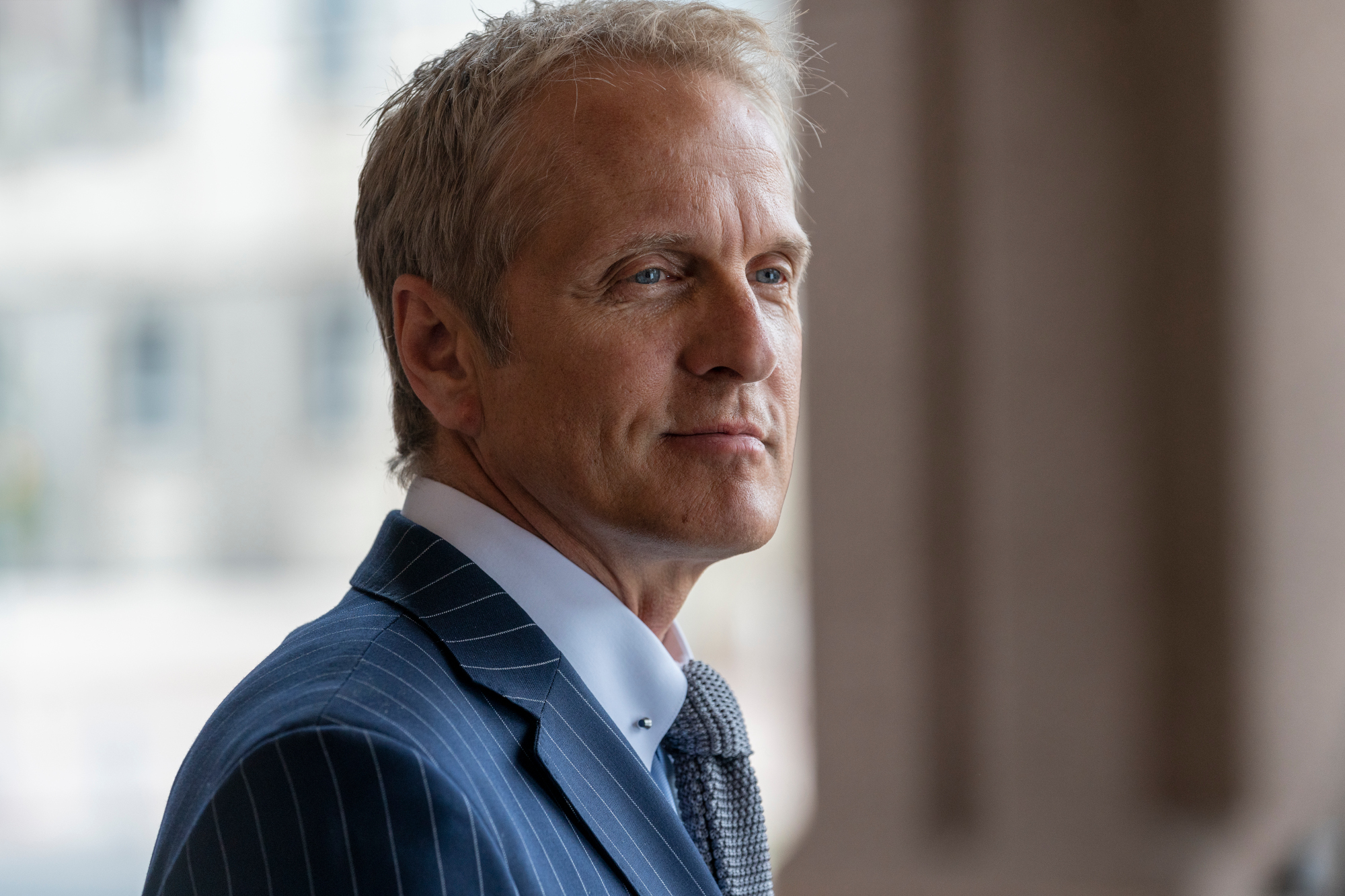 Patrick Fabian as Howard Hamlin in 'Better Call Saul' Season 5. He's wearing a blue suit and smiling.