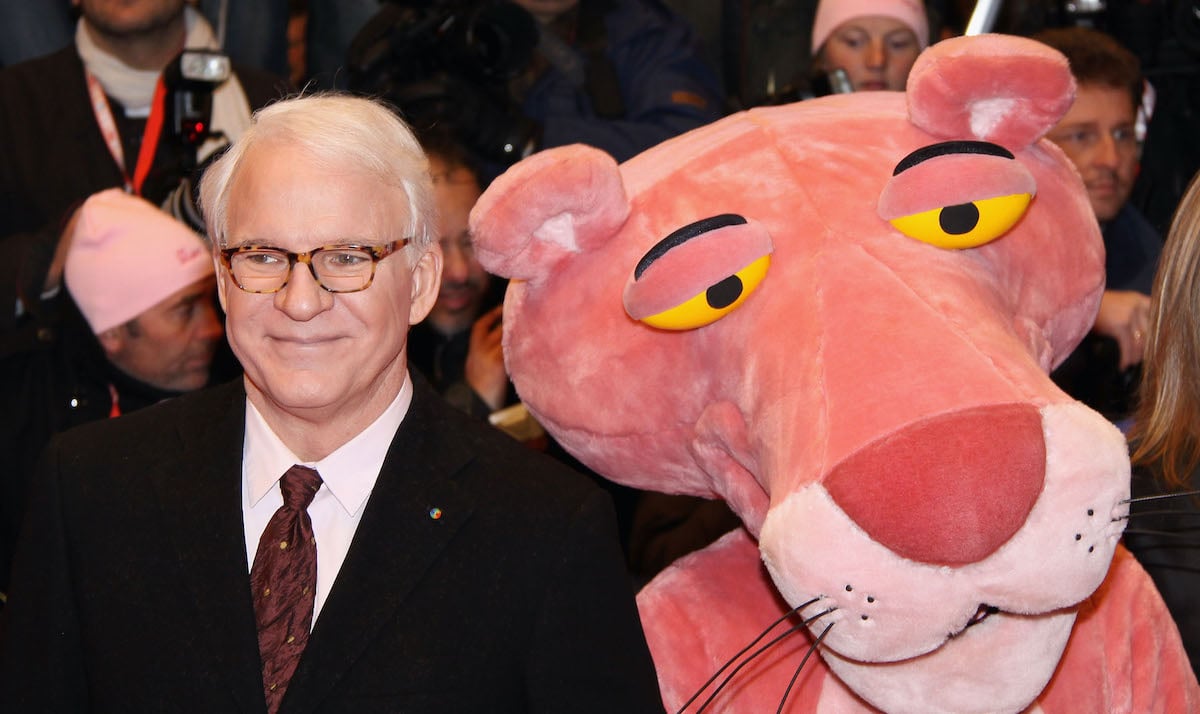Steve Martin wears a suit and stands next to the Pink Panther