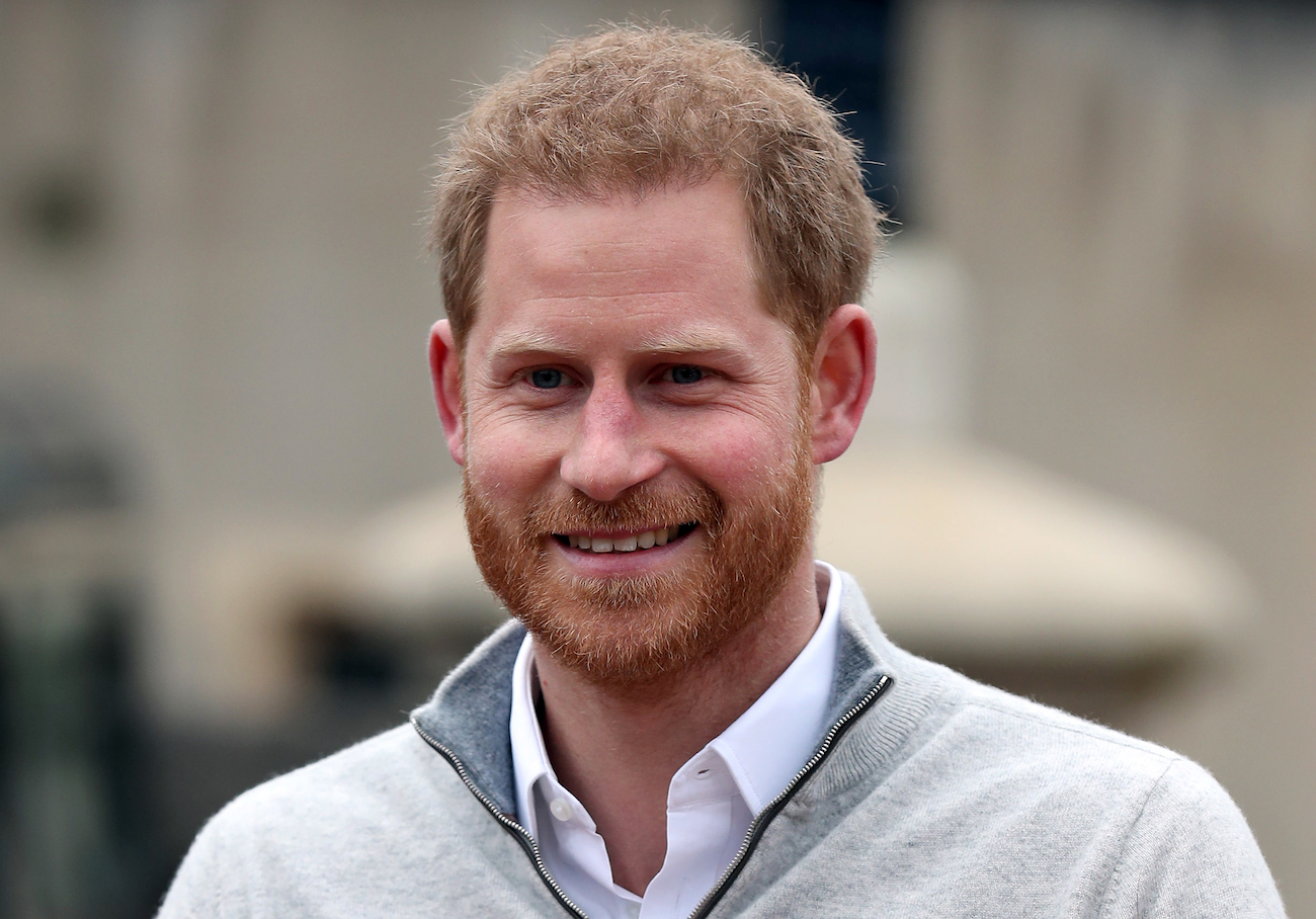 Prince Harry looking on while wearing a gray outfit