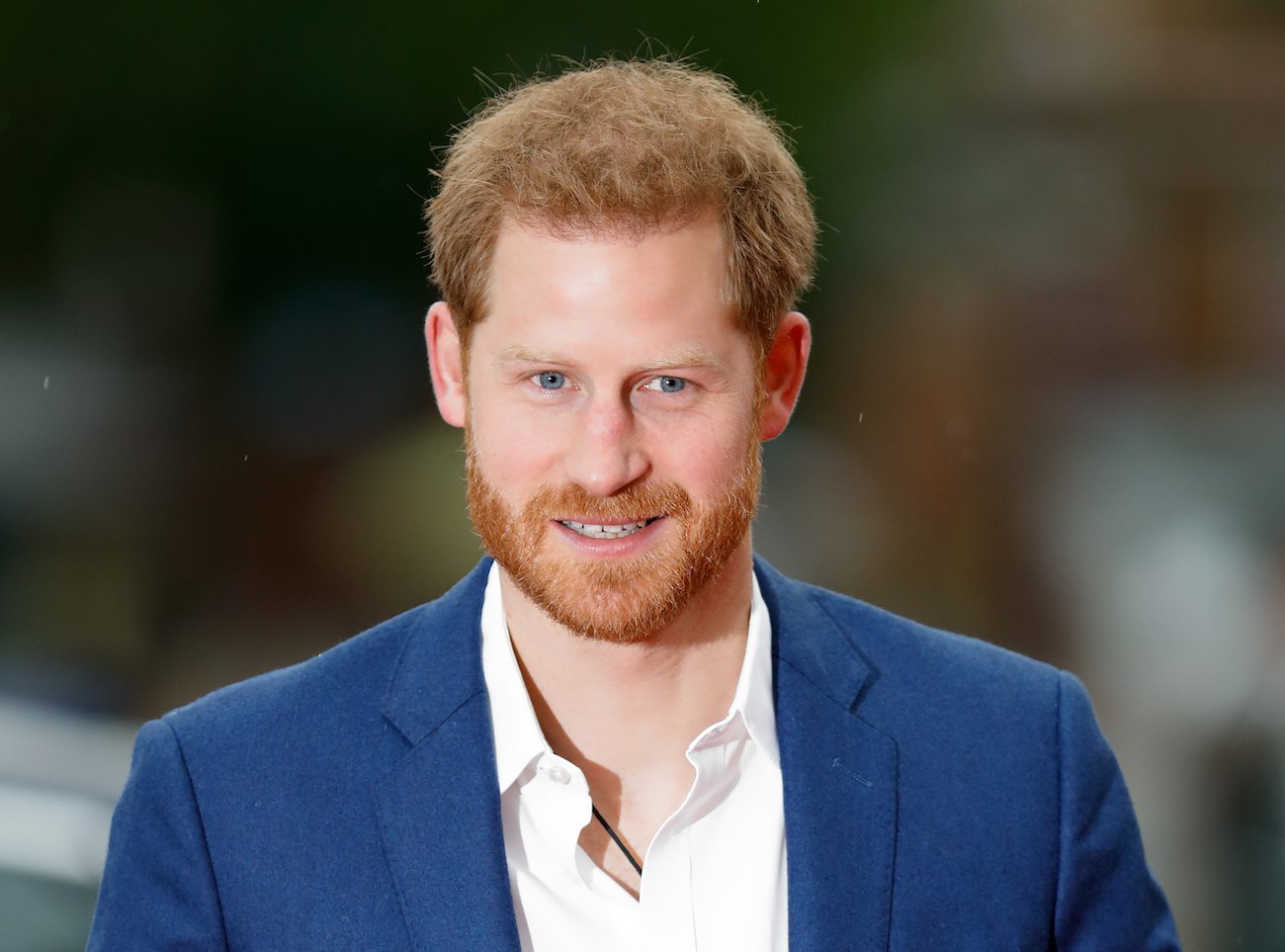 Prince Harry looking on while wearing a blue jacket