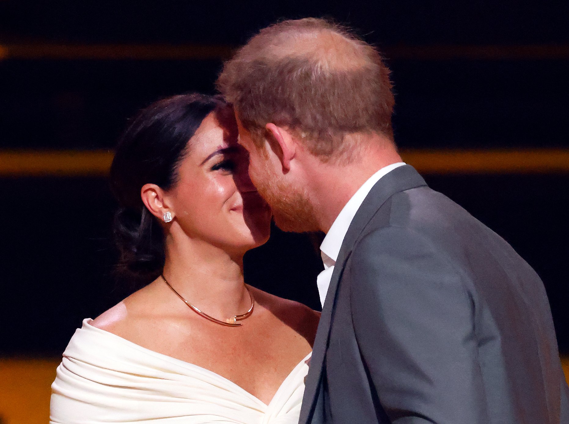 Prince Harry leans in to kiss Meghan Markle onstage