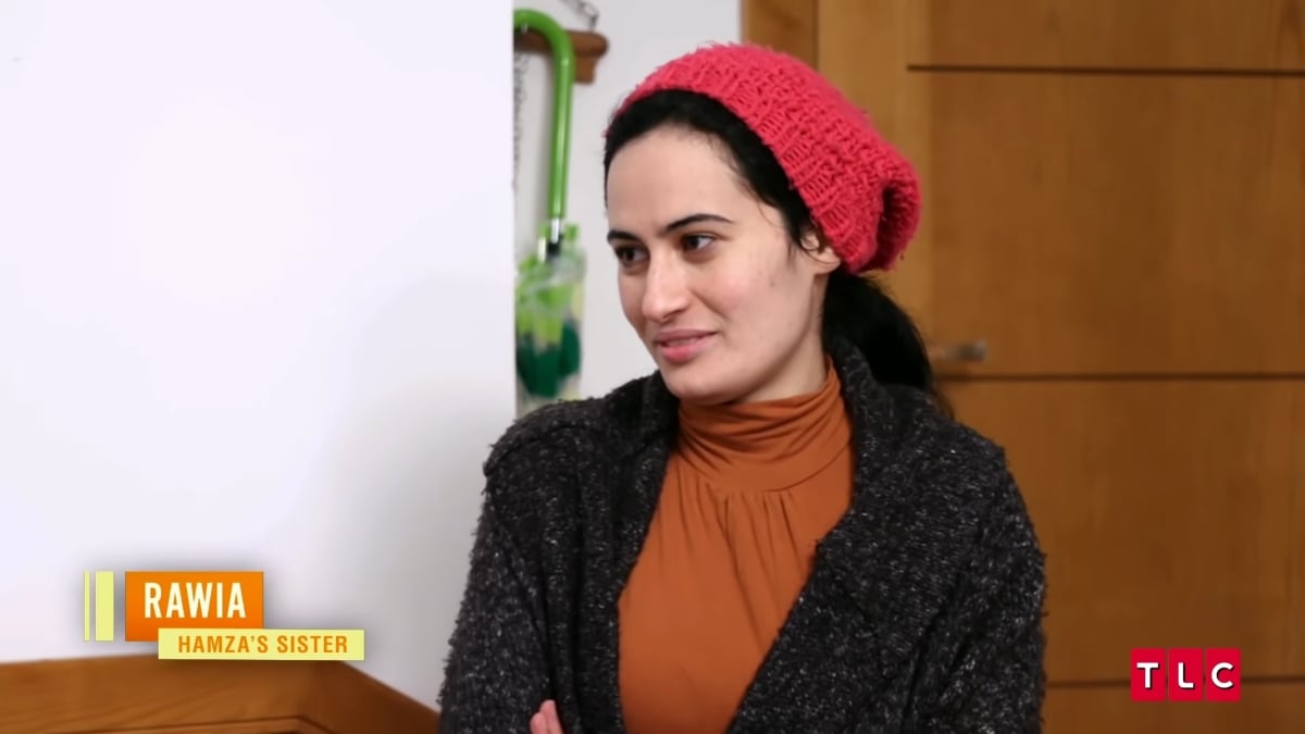 Hamza Moknii's sister, Rawia Moknii wearing a red beanie with a brown shirt and black cardigan on '90 Day Fiancé: Before the 90 Days' Season 5.