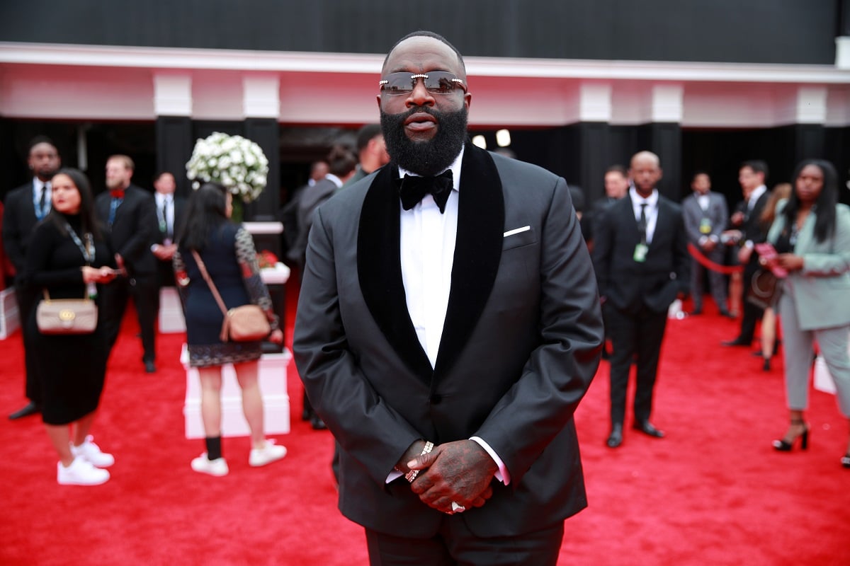 Rick Ross posing while wearing a gray suit.
