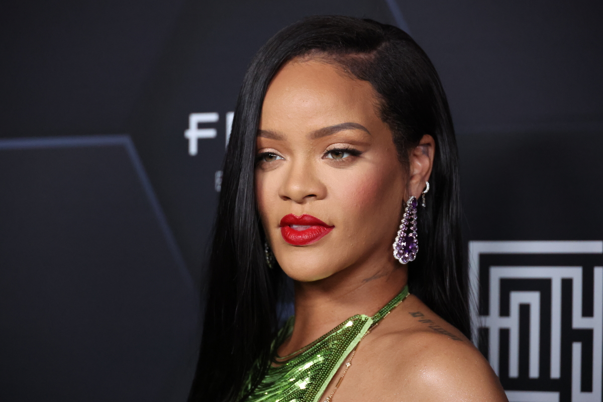Rihanna poses wearing red lipstick at a Fenty Beauty event in LA.
