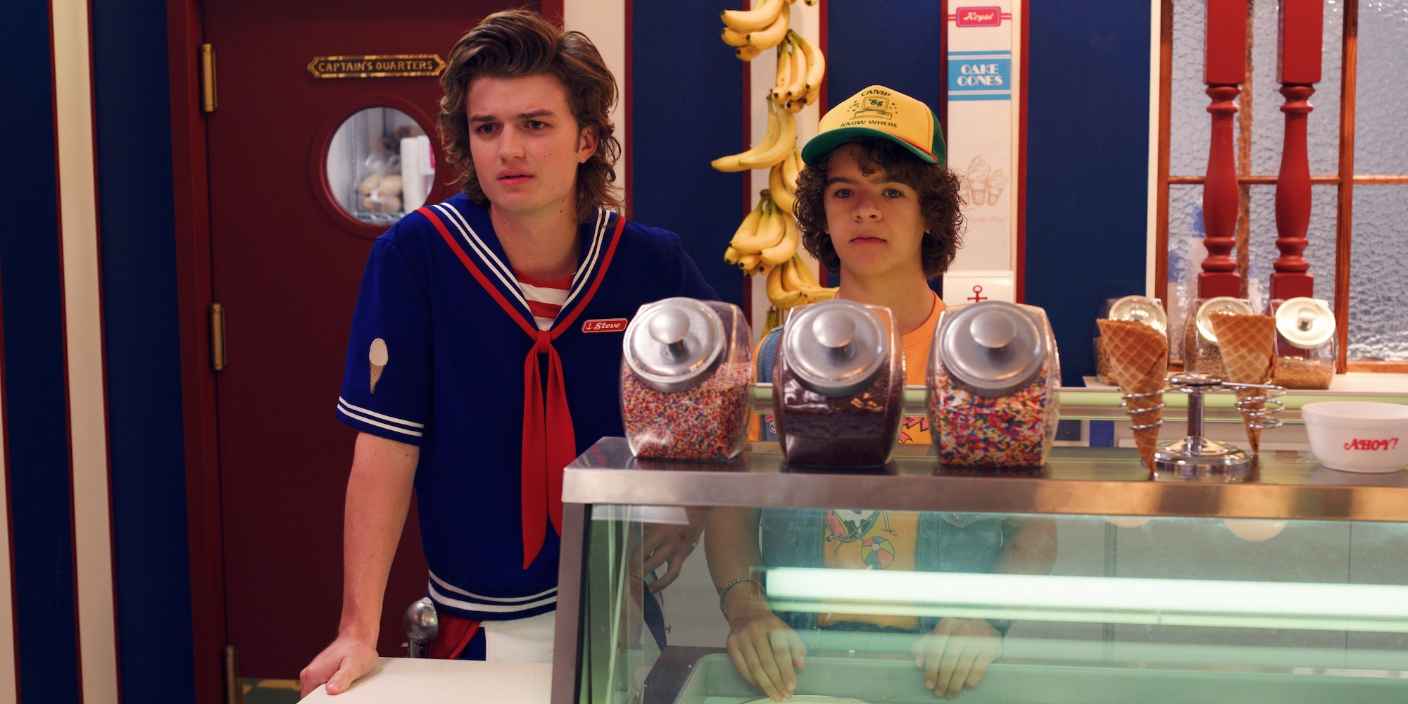 'Stranger Things' fan favorites Steve and Dustin standing behind the counter at Scoops Ahoy in a production still from season 3