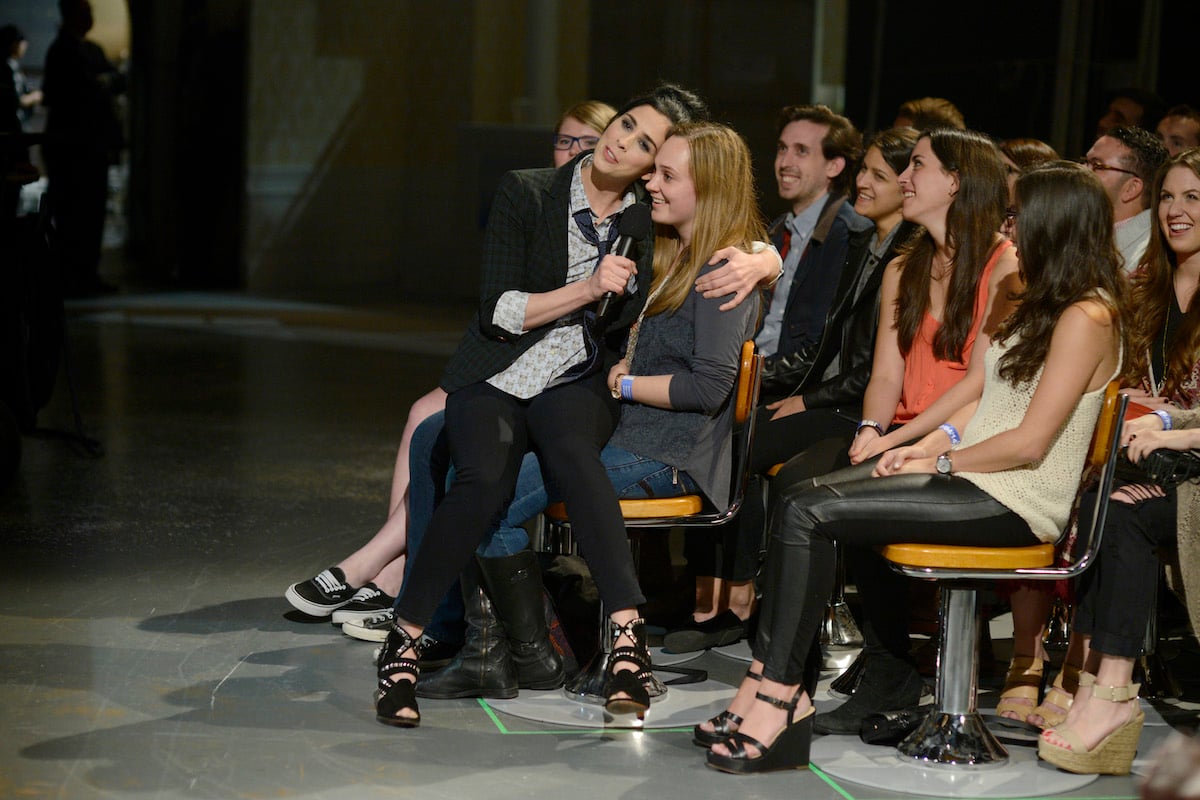 Sarah Silverman sits on an audience member's lap during Saturday Night Live's opening monologue in 2014