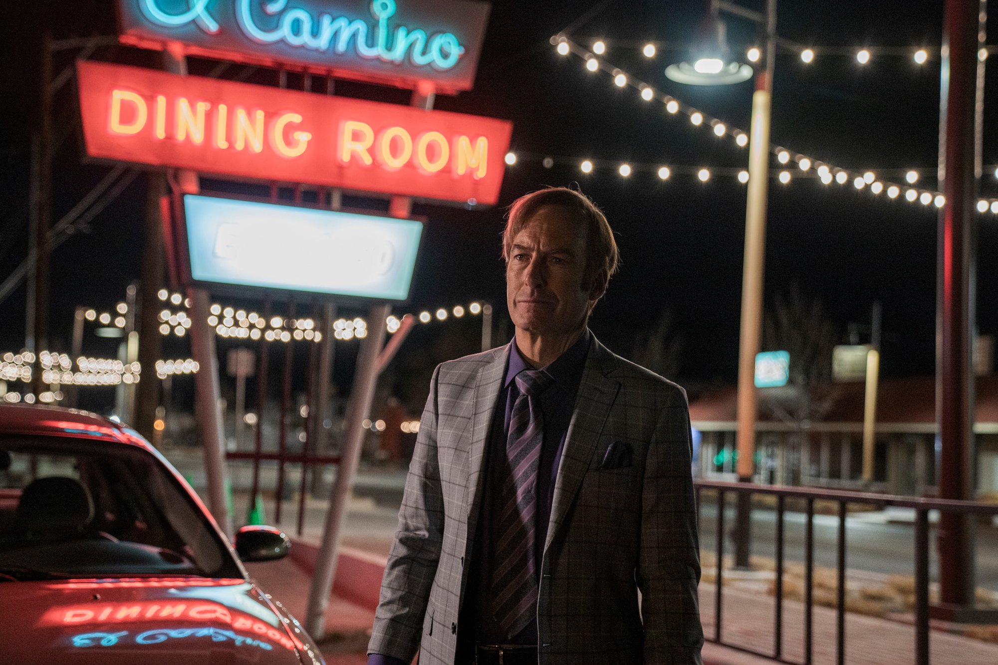 Bob Odenirk as Jimmy McGill/Saul Goodman in 'Better Call Saul' Season 6 Episode 1. He's standing in front of a lit-up sign that says 'El Camino Dining Room'