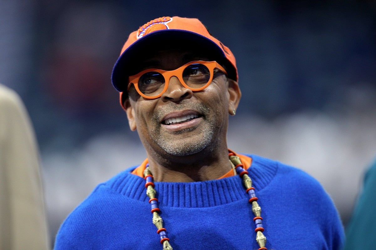 Spike Lee smiling while wearing an orange cap.