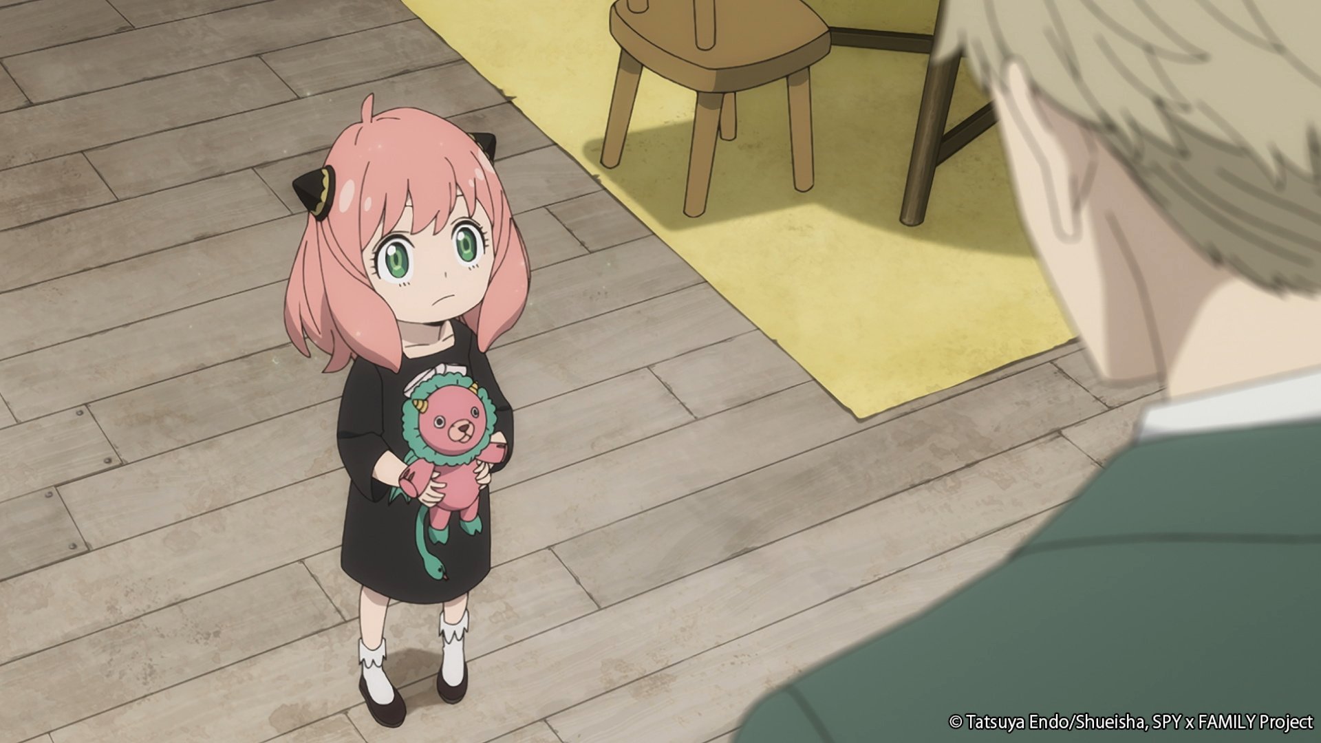 Anya and Loid in episode 1 of 'Spy x Family.' The two are staring at one another while she holds a stuffed lion.