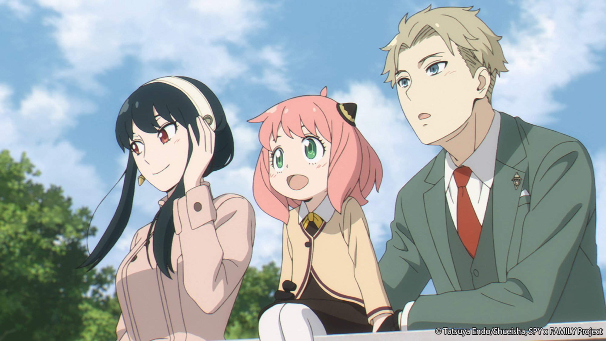 Yor, Anya, and Loid Forger in 'Spy x Family.' They're standing next to one another, wearing nice clothes, and smiling. The sky is blue and cloudy behind them.