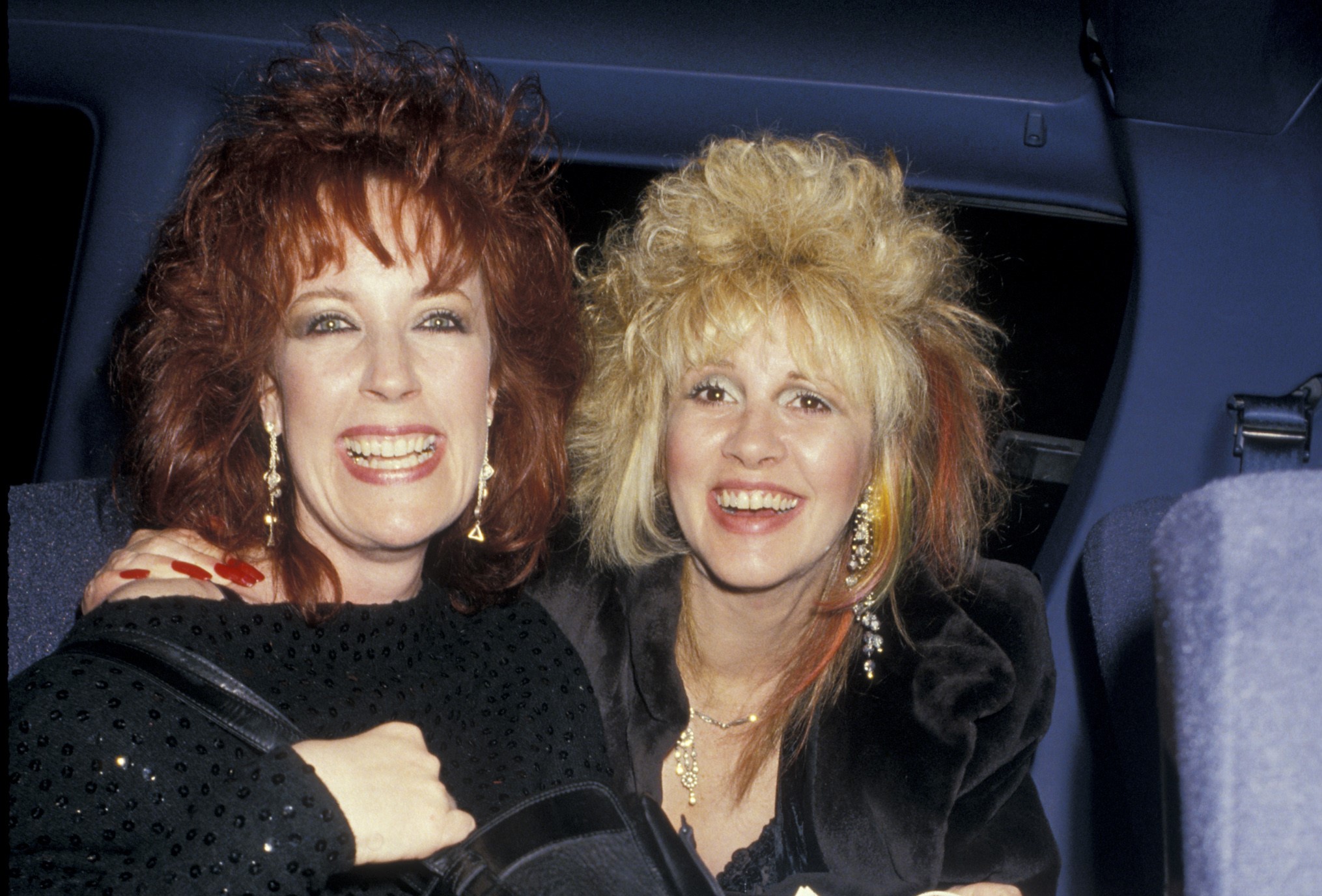 Stevie Nicks and a friend wear black and sit in a car together.