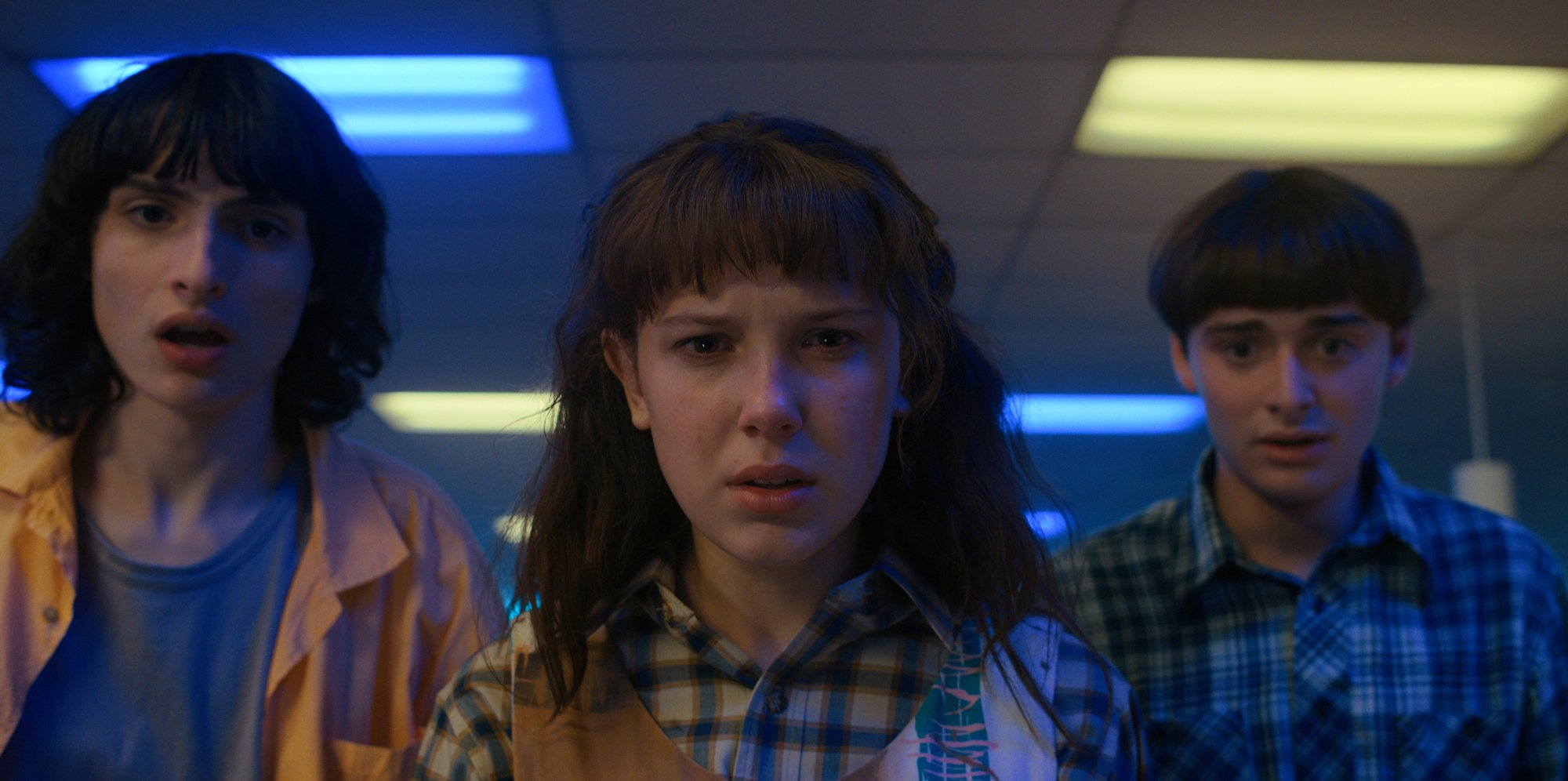 'Stranger Things' Season 4 still showing Eleven, with all her hair, standing between Mike and Will at a roller rink.