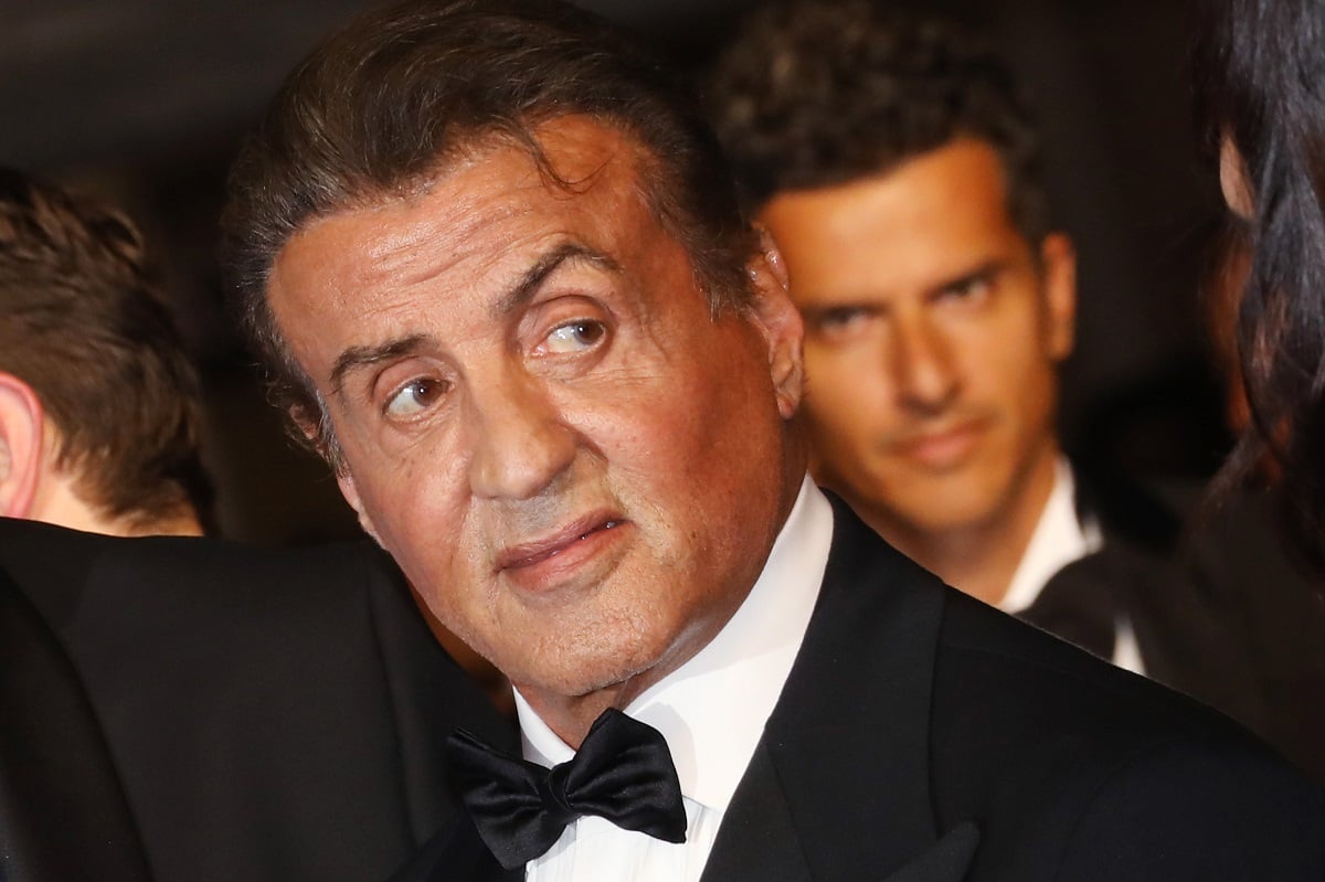 Sylvester Stallone smirking while wearing a suit.