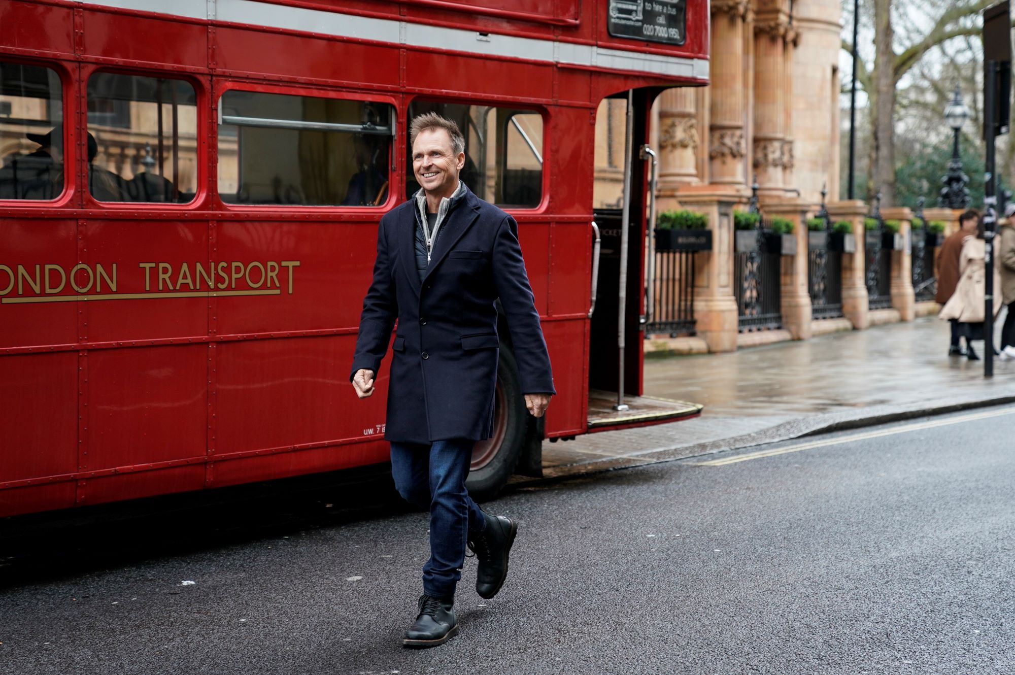 'The Amazing Race' Season 34 host Phil Keoghan wears a black coat, jeans, and black boots.