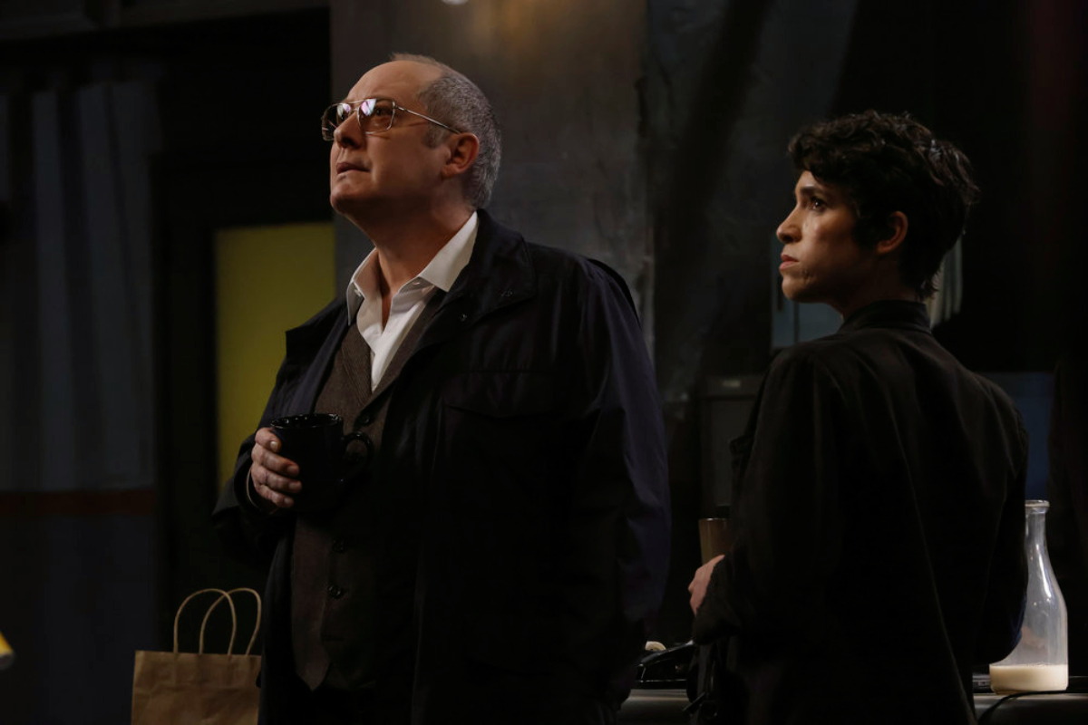 James Spader as Raymond "Red" Reddington and Diany Rodriguez as Weecha Xiu in The Blacklist Season 9. Red wears glasses and Weecha stands next to him.