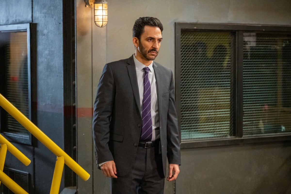 Amir Arison as Aram Mojtabai in The Blacklist Season 9. Aram wears a suit and tie and looks serious.