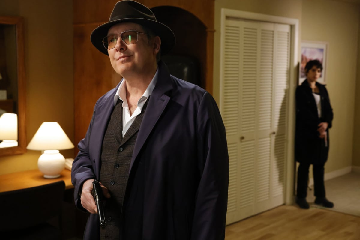 Red and Weecha in The Blacklist Season 9. Red holds a gun and Weecha stands against the wall.
