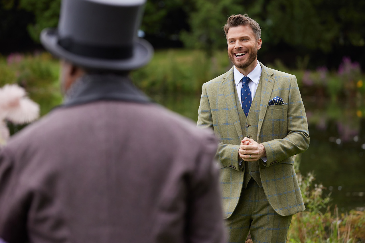 Rick Edwards wears a suit by a pond in front of the suitors on 'The Courtship'.