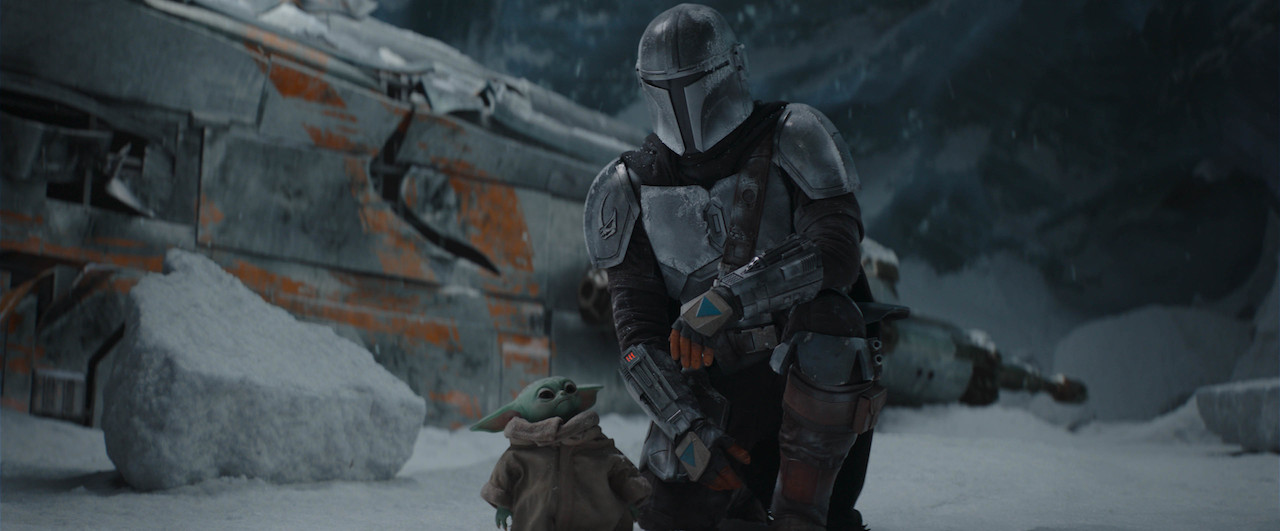 The Mandalorian, played by Pedro Pascal, kneels next to Grogu in 'The Mandalorian' Season 2. 