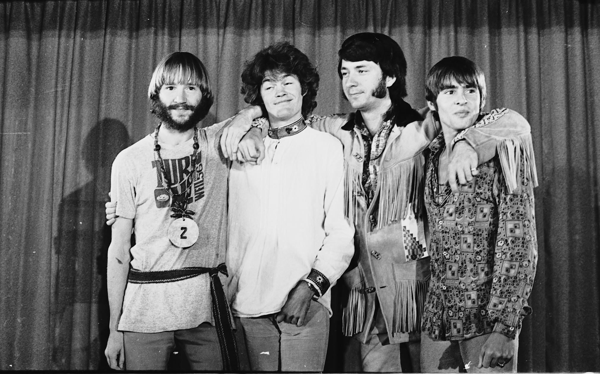 The Monkees' Peter Tork, Micky Dolenz, Mike Nesmith, and Davy Jones in front of a curtain