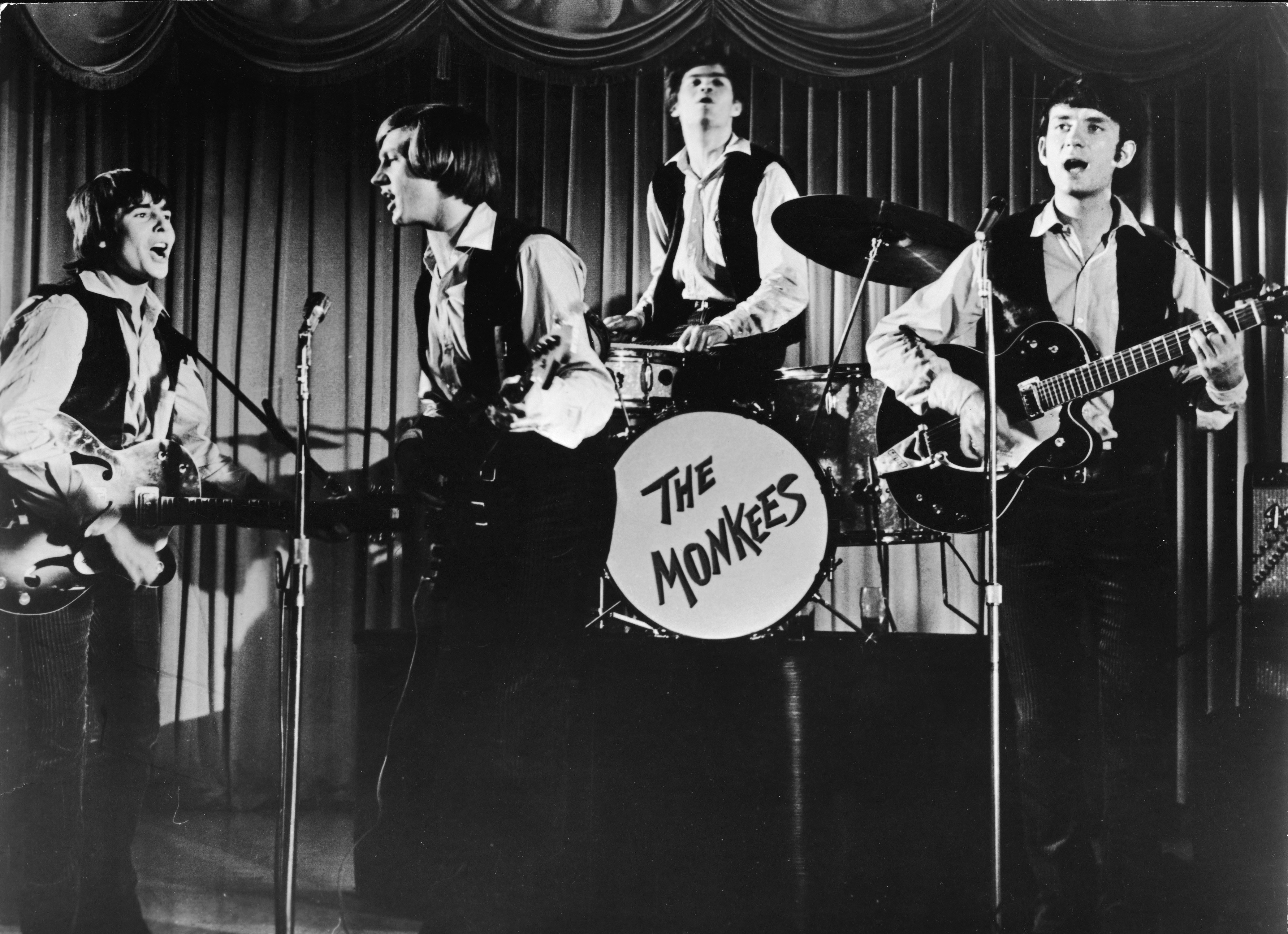 The Monkees' Davy Jones, Peter Tork, Micky Dolenz, and Mike Nesmith in front of a curtain