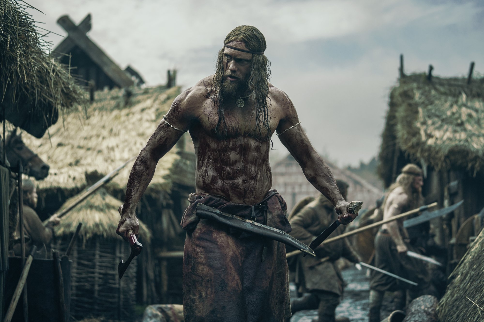 'The Northman' Alexander Skarsgård as Amleth shirtless covered in blood holding a weapon in each hand
