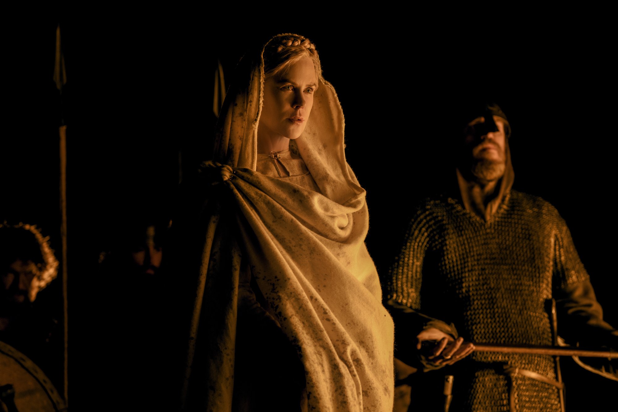 'The Northman' Nicole Kidman as Queen Gudrún wearing a white costume with a guard standing behind her